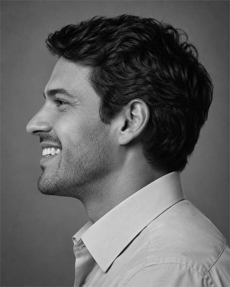 Homem sorrindo, de perfil, em preto e branco